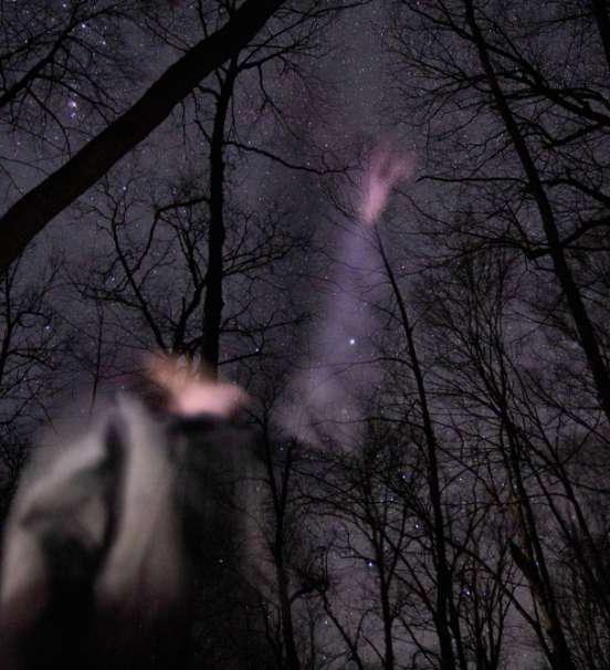 照片 of student studying night sky in winter woods