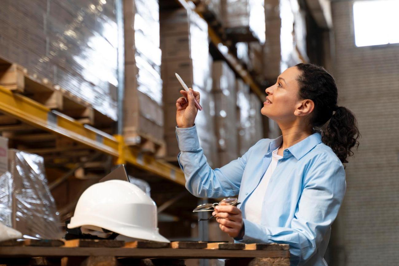 Woman pointing and noting boxes in a warehouse. Image by Freepik.